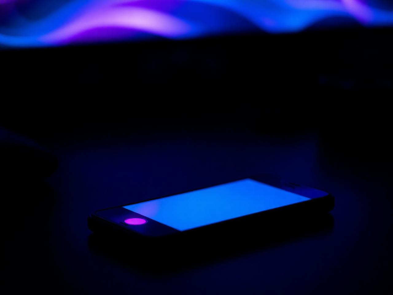 Móvil iluminado de noche con halo de luz cálida insinuando una conversación.